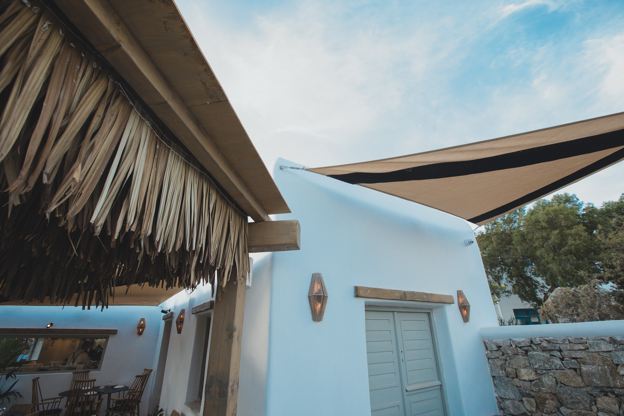 Cycladic restaurant in Mykonos with white architecture, timber pergolas and natural materials