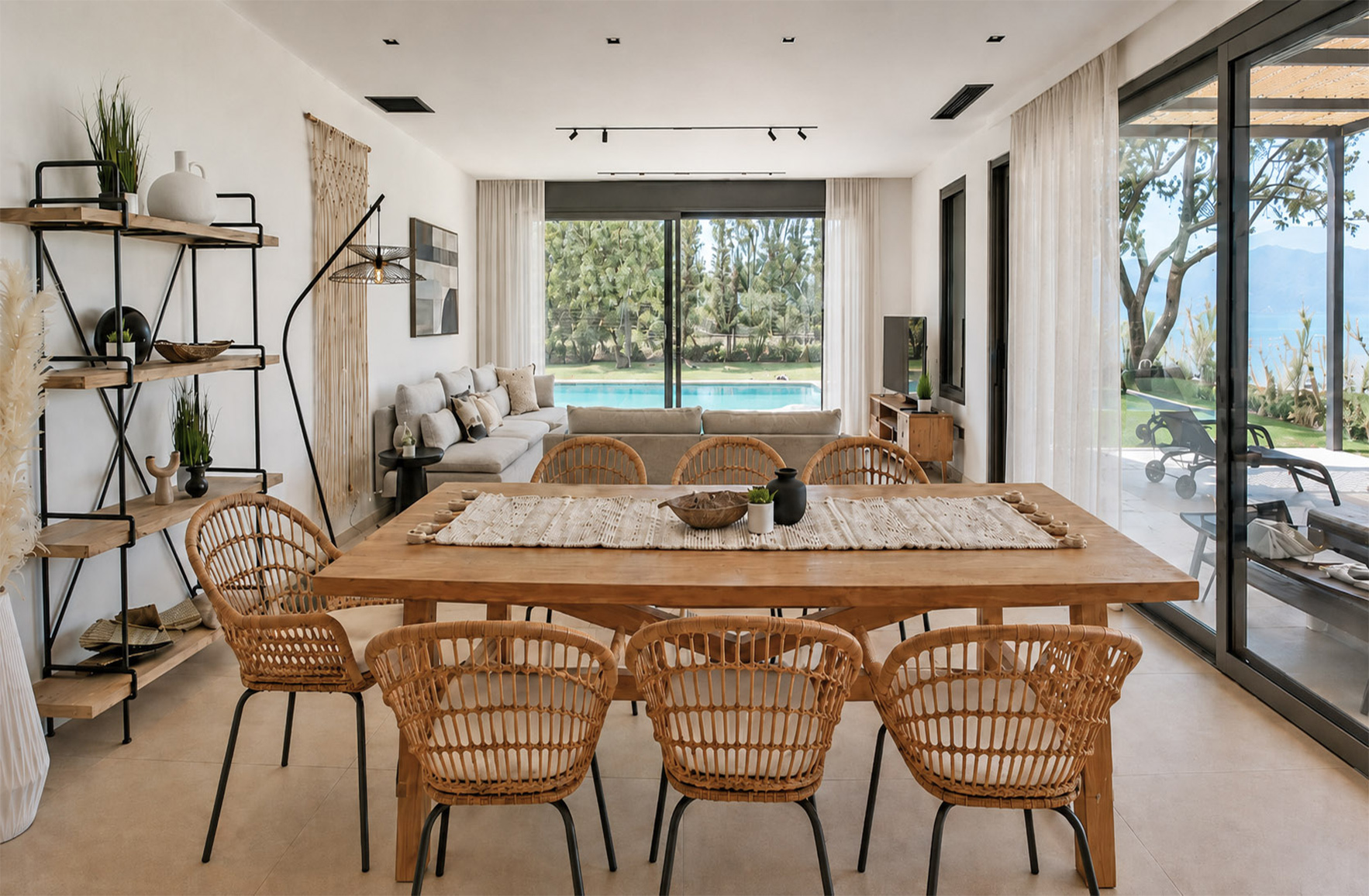 Open-plan kitchen and dining area with a wooden table, dining chairs and part of the adjoining sofa in a Skaloma holiday home