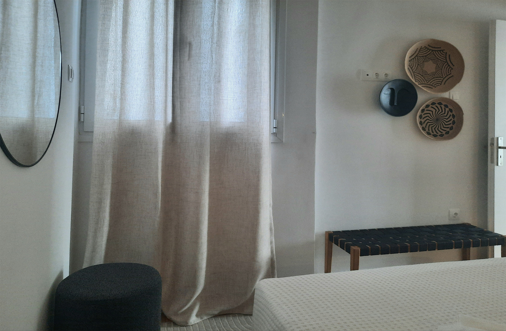 Bedroom detail with sheer curtains, bench and natural textures in the Plaka guest apartment