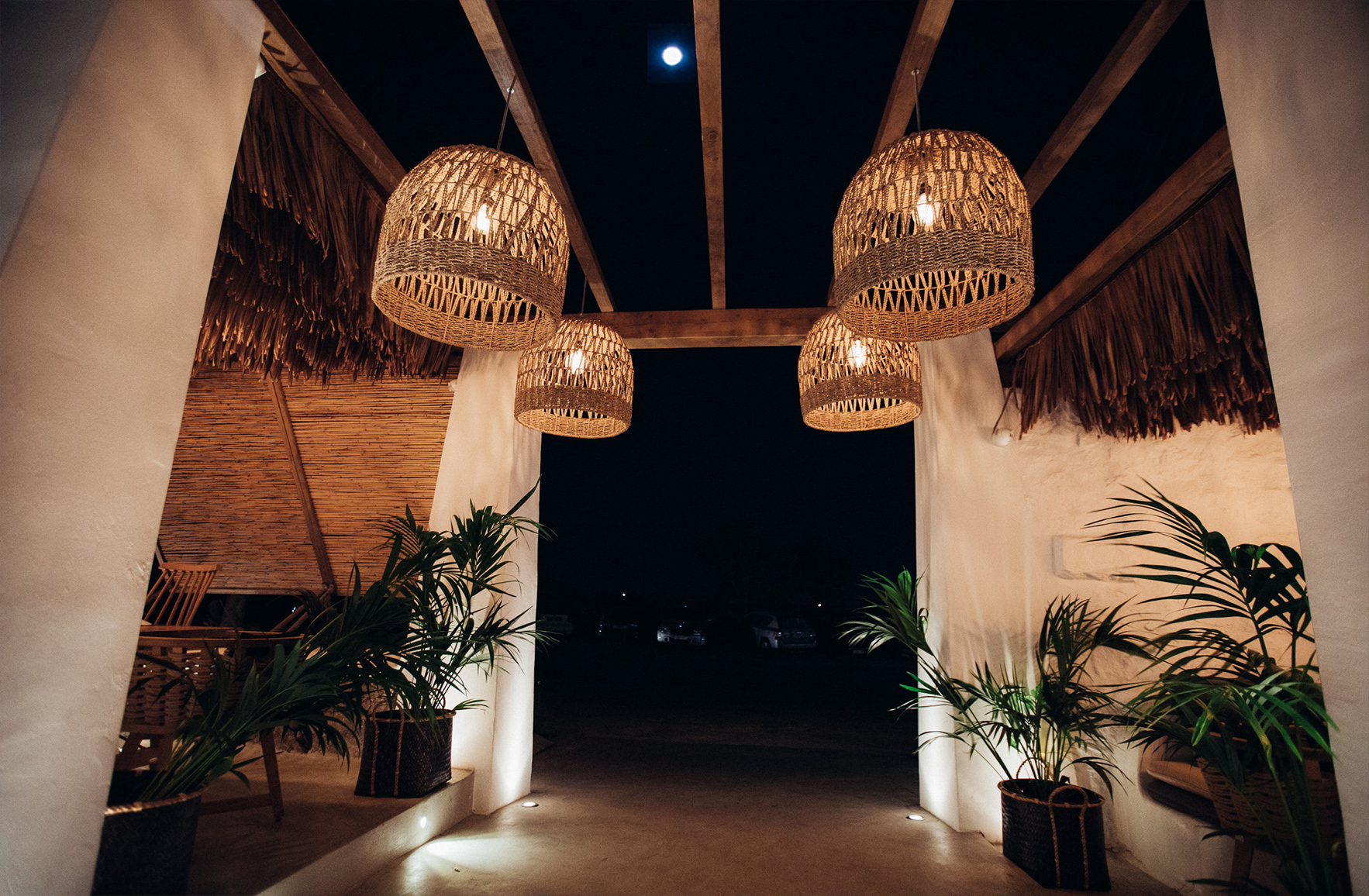 Restaurant entrance in Mykonos framed by white walls, timber and warm architectural lighting