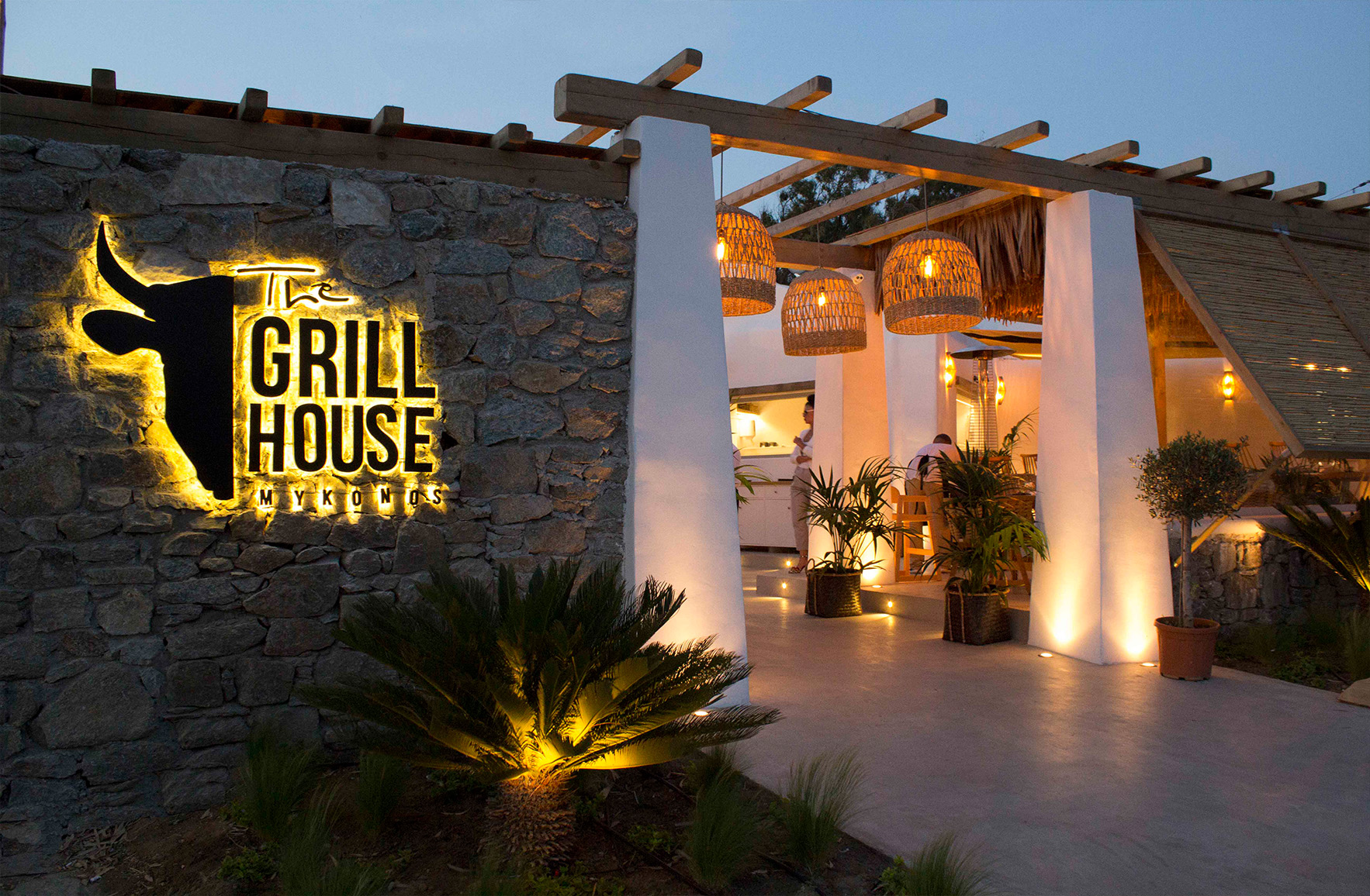 Natural stone walls and Woven pendant lights illuminating a Mediterranean restaurant entrance in Mykonos